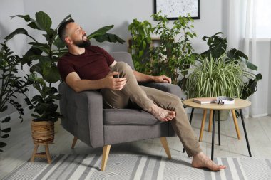 Uyum. Evdeki rahat koltukta dinlenen adam.