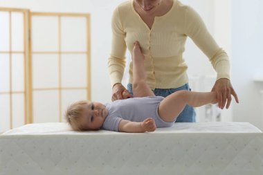 Anne, sevimli bebeğiyle evde masasını değiştirip oynuyor.