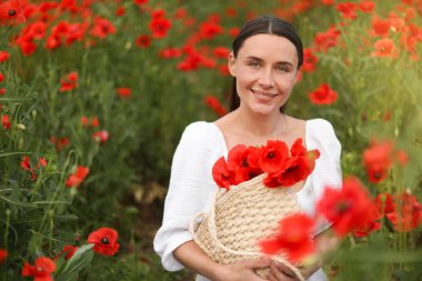 Kırmızılı gelincik çiçekleri arasında çantasıyla gülümseyen kadın portresi