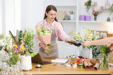 Çiçek buketi olan bir çiçekçi müşteriden alışveriş merkezinden ödeme alıyor.
