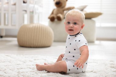 Işık odasında halının üzerinde oturan tatlı bebek.