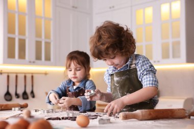 Yemek tarifi. Küçük çocuklar mutfaktaki masada kurabiye için para kazanıyorlar.