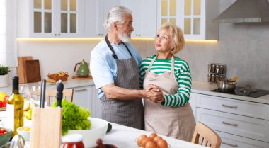 Mutfakta birlikte yemek pişirirken dans eden yaşlı çift.