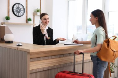 İçerideki resepsiyonda çalışan gülümseyen resepsiyonist.