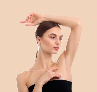 Koltukaltı epilasyonu. Bej arka planda tüyler alındıktan sonra koltukaltında pürüzsüzlük gösteren kadın.