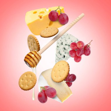 Mercan eğimli arka planda havada peynir tahtası ürünleri. Farklı peynir, üzüm, kraker ve bal çeşitleri.
