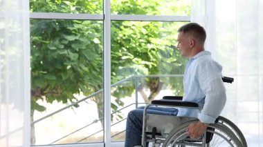 Pencere kapalı yakınındaki tekerlekli sandalyede genç adam