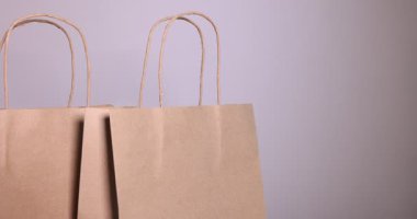 Gri arkaplana kese kağıdı koyan kadın, yakın plan.