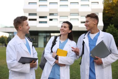 Açık hava binasının yakınında üniformalı tıp öğrencileri.