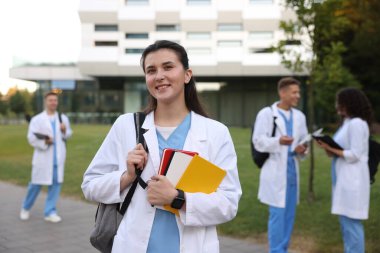 Dışarıda defterleri olan üniformalı bir tıp öğrencisi. Seçici bir odak noktası.