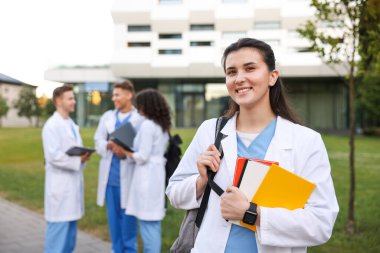 Dışarıda defterleri olan üniformalı bir tıp öğrencisi. Seçici bir odak noktası.