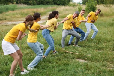 Takım oluşturma. Dışarıda halatla çekme oyunu oynayan bir grup mutlu insan.