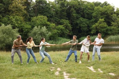 Takım oluşturma. Dışarıda halatla çekme oyunu oynayan bir grup mutlu insan.
