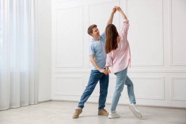 Mutlu çift evde beyaz duvarın yanında dans ediyor.