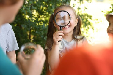 Doğada büyüteç olan bir grup çocuk, seçici odaklanma
