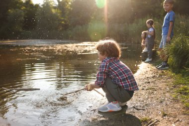 Şirin küçük çocuk ve diğer çocuklar gölün doğasında oynuyorlar, seçici bir odaklanma.