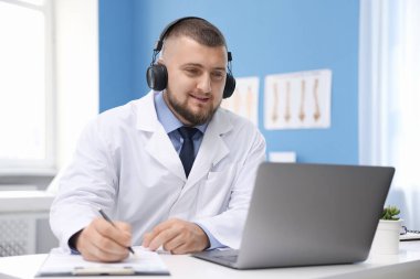 Kulaklıklı doktor içeride bilgisayarla online danışmanlık yapıyor.