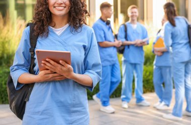 Açık hava binasının yakınında sırt çantası ve tabletli bir tıp öğrencisi, seçici odaklı.