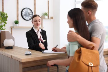 Otel resepsiyonunda müşterilerle çalışan bir resepsiyonist.