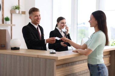 Gülümseyen resepsiyonistler ve müşteriler oteldeki resepsiyonda