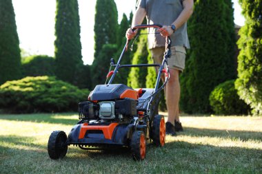Bahçede çim biçme makinesiyle çimen biçen adam, yakın plan.