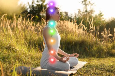 Lotus 'ta meditasyon yapan kadın doğada poz veriyor. Yedi çakra parlıyor