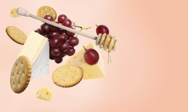 Mercan eğimli arka planda havada peynir tahtası ürünleri. Farklı peynir, üzüm, kraker ve bal çeşitleri.