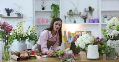 Dükkandaki tahta masada dizüstü bilgisayarla çalışan profesyonel bir çiçekçi.