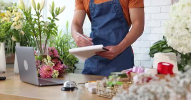 Dükkandaki ahşap masada çalışan profesyonel çiçekçi, yakın plan.