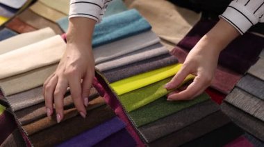 Kadın farklı örnekler arasından kumaşı seçiyor, kapalı alanda, yakın plan.