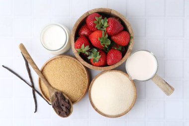 Panna cotta için farklı malzemeler. Süt, şeker, vanilya, çikolata ve çilek beyaz fayanslı masada, düz konum