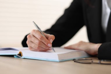 Defterde, tahta masada arka planda kalemle yazı yazan kadın, yakın plan