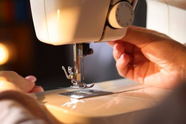 Bulanık arkaplanda dikiş makinesi iğnesi, makro görünümü olan kadın