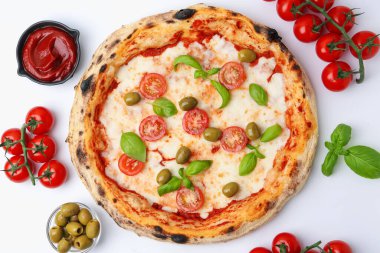 Lezzetli pizza ve malzemeler beyaz masada, düz yerde.