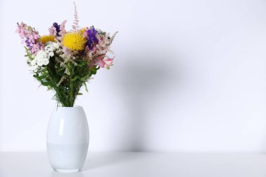 Beyaz masadaki vazoda güzel çiçekler, metin için boşluk