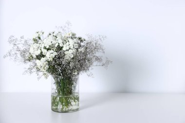 Beyaz masadaki vazoda güzel çiçekler, metin için boşluk