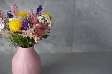 Gri masadaki vazoda güzel çiçekler, yakın plan. Metin için boşluk