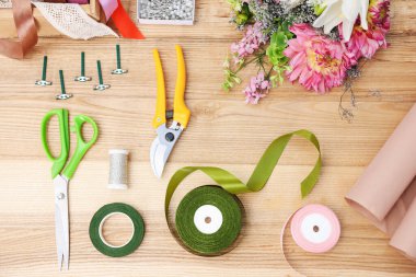 Çiçekçi. Çiçekler, mezhepçiler, makas ve kurdeleler ahşap masa, üst manzara