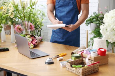 Dükkandaki ahşap masada çalışan profesyonel çiçekçi, yakın plan.