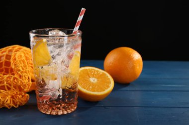 Bardakta portakallı köpüklü su ve mavi ahşap masada taze meyveler, yakın plan. Metin için boşluk