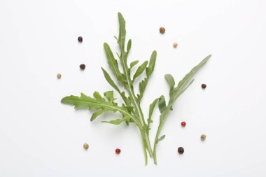 Taze yeşil roka yaprakları ve beyaz arka planda biberler, düz yatıyordu.