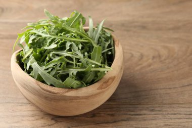 Tahta masadaki kasede taze yeşil roka yaprakları, yakın plan. Metin için boşluk