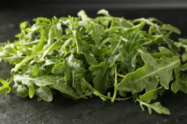 Taze yeşil roka yaprakları siyah masada, yakın plan.