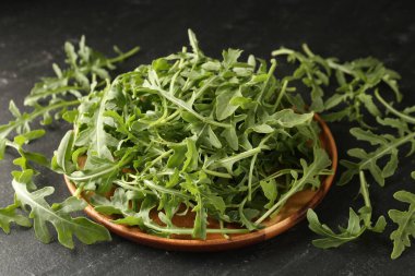 Taze yeşil roka yaprakları siyah masada, yakın plan.