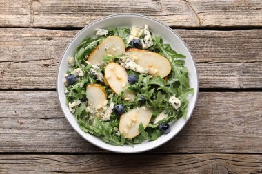 Lezzetli salata roka, armut, mavi peynir, fıstık ve böğürtlenler ahşap masada, üst manzara