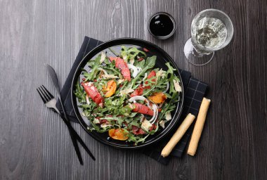 Lezzetli salata roka, peynir, greyfurt, sebze ve balzamik sos. Koyu ahşap masada servis ediliyor.