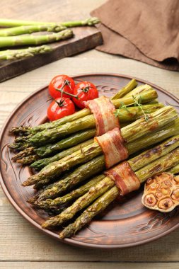 Ahşap masada domuz pastırması ile servis edilen lezzetli kuşkonmaz, yakın plan.