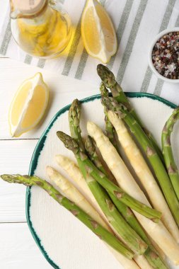 Beyaz ahşap masada farklı çiğ kuşkonmaz ve baharatlar var.