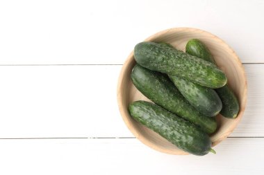 Beyaz ahşap masada, tabakta taze salatalıklar, üst manzara. Metin için boşluk