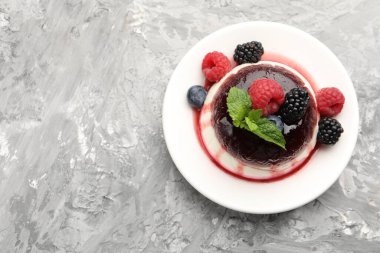 Böğürtlenli ve reçelli leziz panna cotta, açık gri masa, üst manzara. Metin için boşluk
